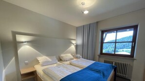 Un dormitorio con cama, mesitas de noche, una ventana con vistas y una lámpara en el techo.