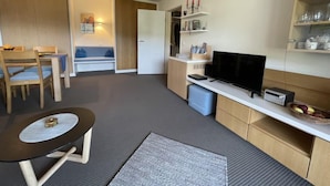 Un espacio habitable compacto con kitchenette, comedor y zona de estar.