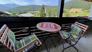 Un espacio al aire libre cubierto con una mesa y sillas, con vistas a un paisaje montañoso.