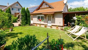 Una casa con techo inclinado, paneles solares, un jardín y una zona de barbacoa.
