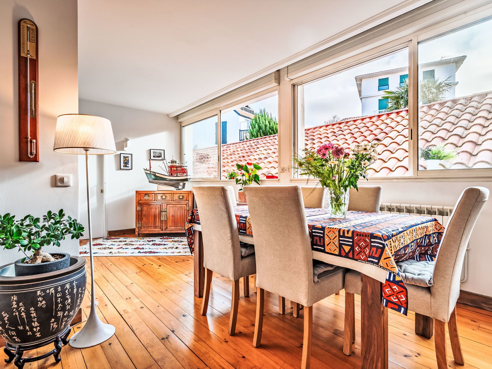 A dining area with a wooden table, beige chairs, and a vase of flowers.