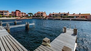 A waterfront property with a wooden dock extending into the water, surrounded by multi-story buildings with balconies. - Les Brigantins by Interhome (Le Barcarès)