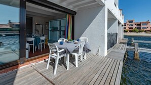 A wooden deck with a table and chairs, overlooking a body of water. - Les Brigantins by Interhome (Le Barcarès)