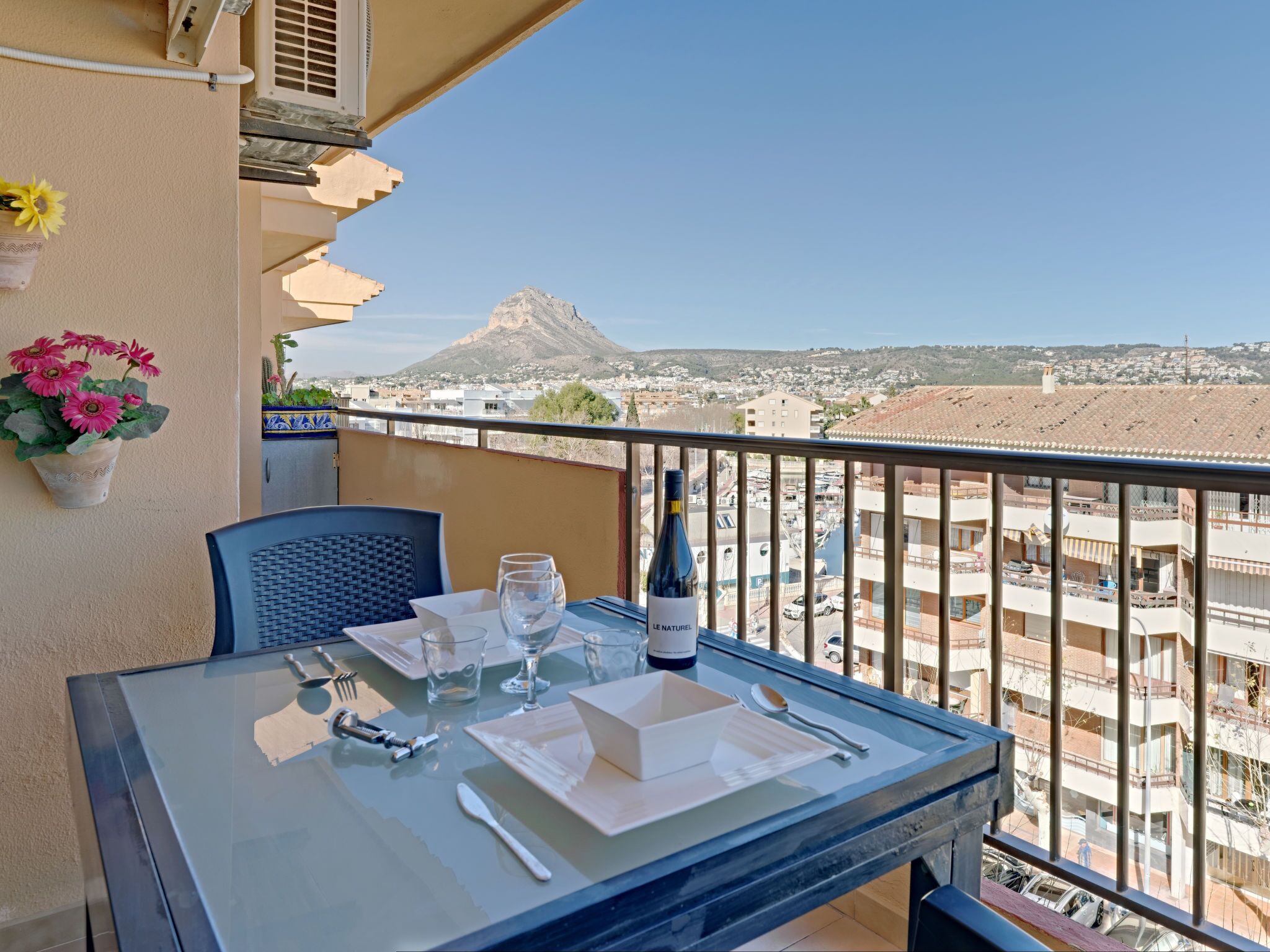 Un balcón con una mesa lista para dos personas, con vistas a la ciudad y a la montaña.