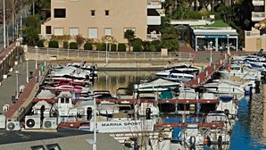 Ein Yachthafen mit angestaubten Booten, ein Gebäude mit der Aufschrift "MARINA SPORT" und ein Schild für "AMARRIS 152".
