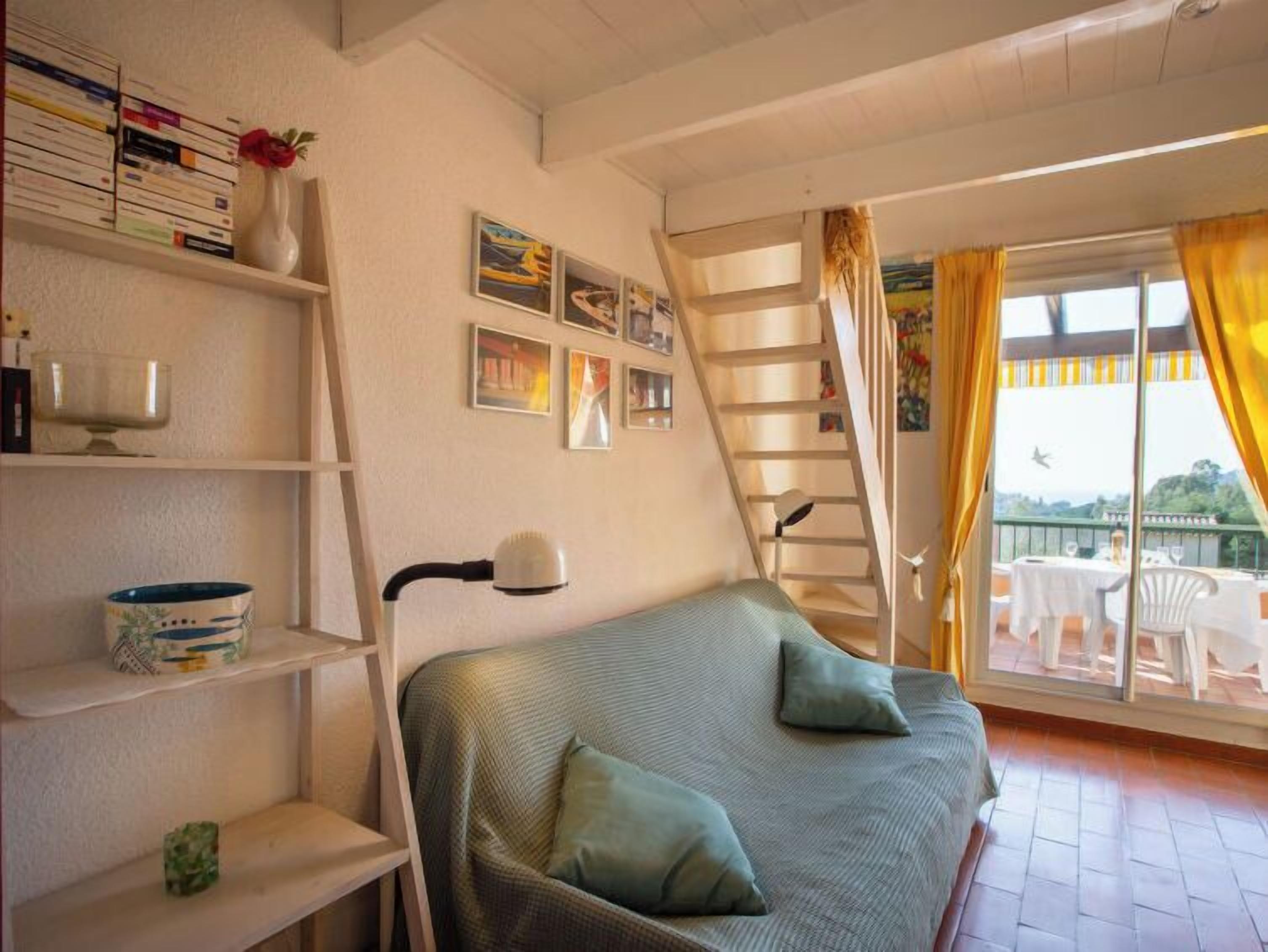Ein gemütliches Zimmer mit einem Bett, einem Bücherregal, einer Leiter und einem Balkon mit Sitzgelegenheit.