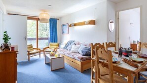 Una sala de estar acogedora con un sofá, sillas, una mesa de comedor y una zona de cocina con estufa.