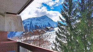 Un balcón con mesa y sillas, con vista a una montaña nevada y un cielo azul despejado.