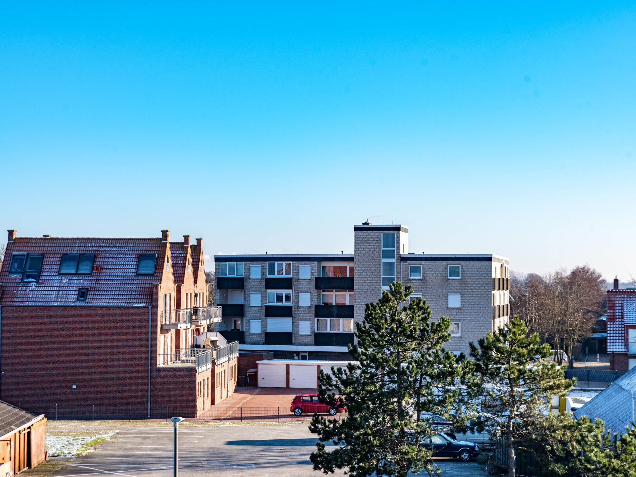 A multi-story residential building with a parking area in front.