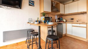 A compact kitchen with a central island, stools, a microwave, and a stove.