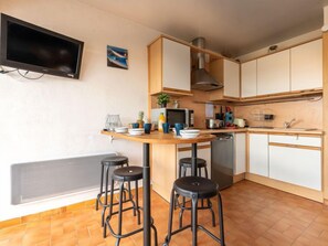 Une cuisine compacte dotée d’un îlot central, de tabourets, d’un four à micro-ondes et d’une cuisinière.