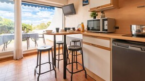 A compact kitchen with a dining area, a TV mounted on the wall, and a view of the outdoors.
