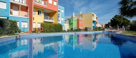 A swimming pool with colorful buildings in the background.