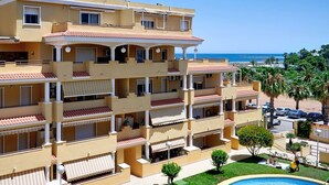 Un hotel de varios pisos con balcones, piscina y vista a la playa.
