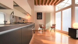 A modern kitchen with a built-in island, a dining area with two chairs, and large windows allowing natural light. - Apartment Iris by Interhome (Venezia Giudecca)