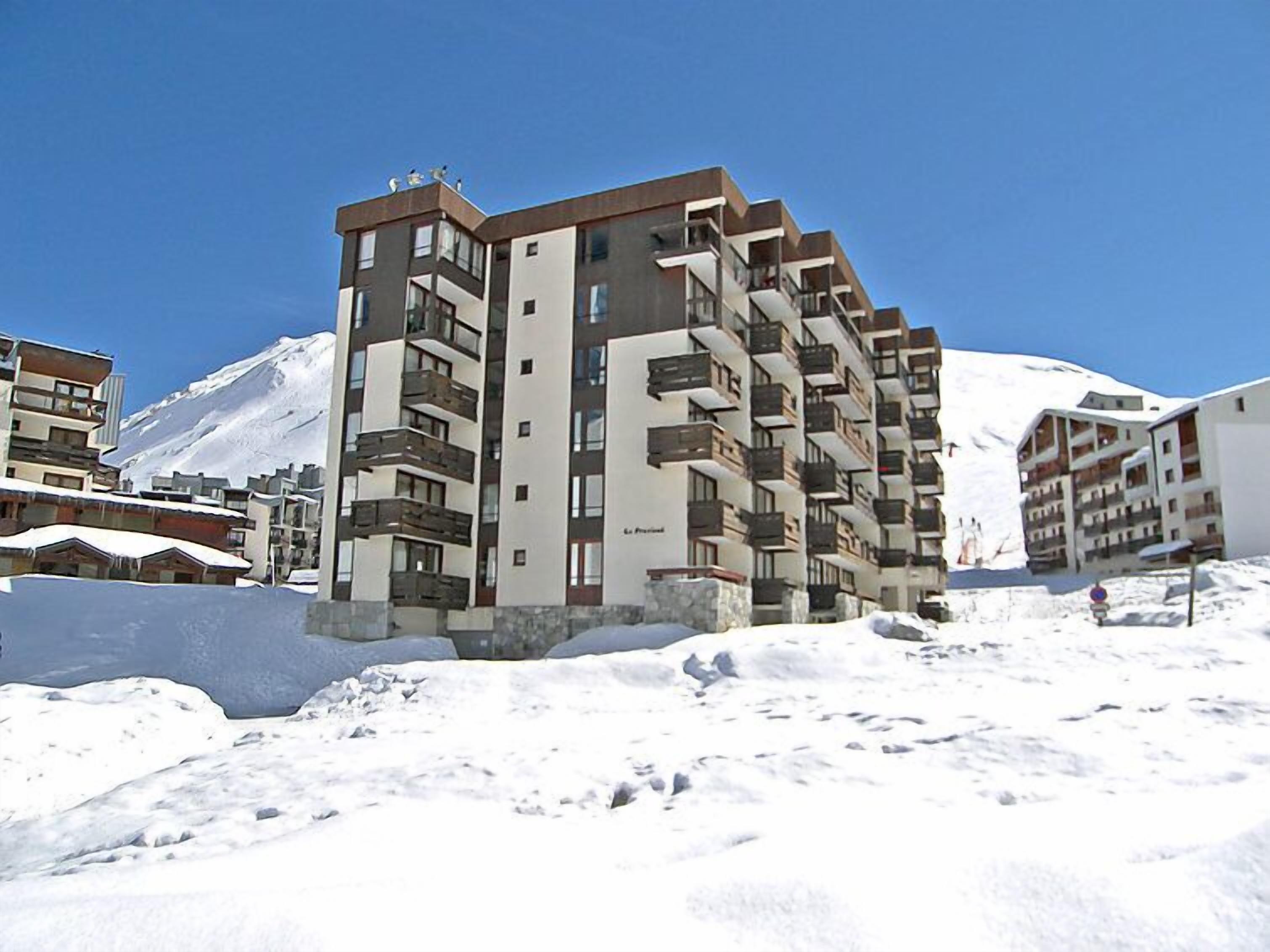 A multi-story hotel with balconies and a snow-covered mountain in the background.