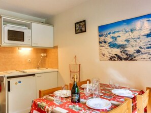 A dining area with a table set for four, a bottle of wine, and a painting of a snowy landscape on the wall.