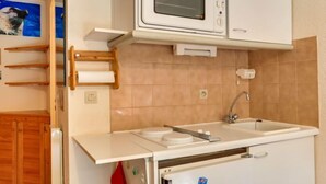 Una cucina compatta con forno a microonde, lavello e mobili in legno.