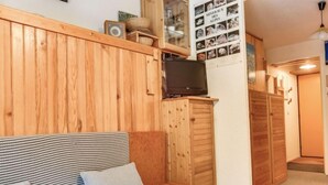 Una stanza accogliente con parete in legno, un divano, una televisione e un mobile vetrina con foto.