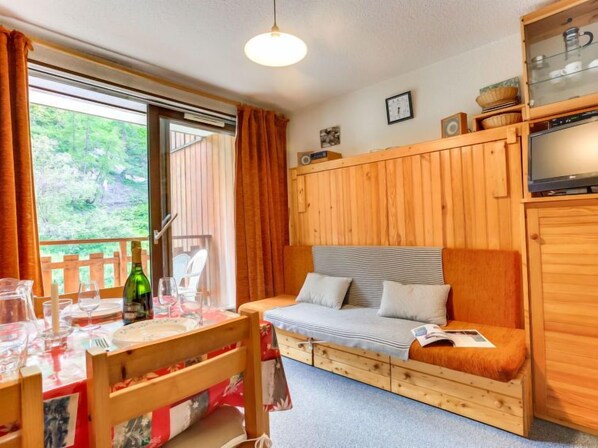 Ein gemütliches Zimmer mit einem Holzbett, einem Esstisch mit Stühlen und einem Fenster mit Vorhängen.