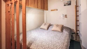 Una camera da letto piccola e accogliente, con soffitto in legno, un letto con biancheria da letto a motivi floreali e una scrivania con lampada.