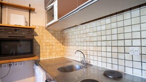 A modern kitchen with a double sink, stainless steel countertops, a built-in oven, and a microwave. - Vanoise 152 by Interhome (Val Thorens)