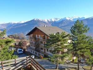 A mountain lodge with a wooden facade, a staircase leading to the entrance, and a view of snow-capped mountains in the background. - Centaure A RS 3 by Interhome (Ovronnaz)