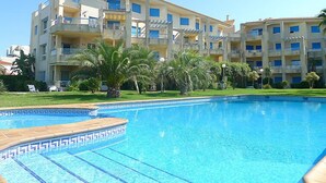 Un hotel con piscina, varios balcones y abundante vegetación.