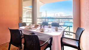 A balcony with a table set for two, overlooking a marina with boats. - Bleu Marine by Interhome (Fréjus)