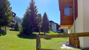 A wooden fence in a grassy area with a building in the background. - Apartment Luchre by Interhome (Zermatt)