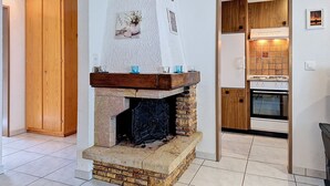 A kitchen with a stone fireplace, wooden cabinets, and a tiled floor. - Apartment Luchre by Interhome (Zermatt)