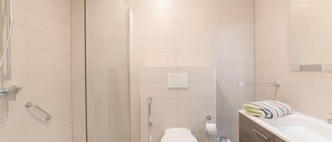 A modern bathroom with a glass-enclosed shower, a toilet, a sink, and a towel rack.