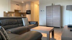 Uma sala de estar moderna com um sofá de couro, uma mesa de centro de madeira e um armário.