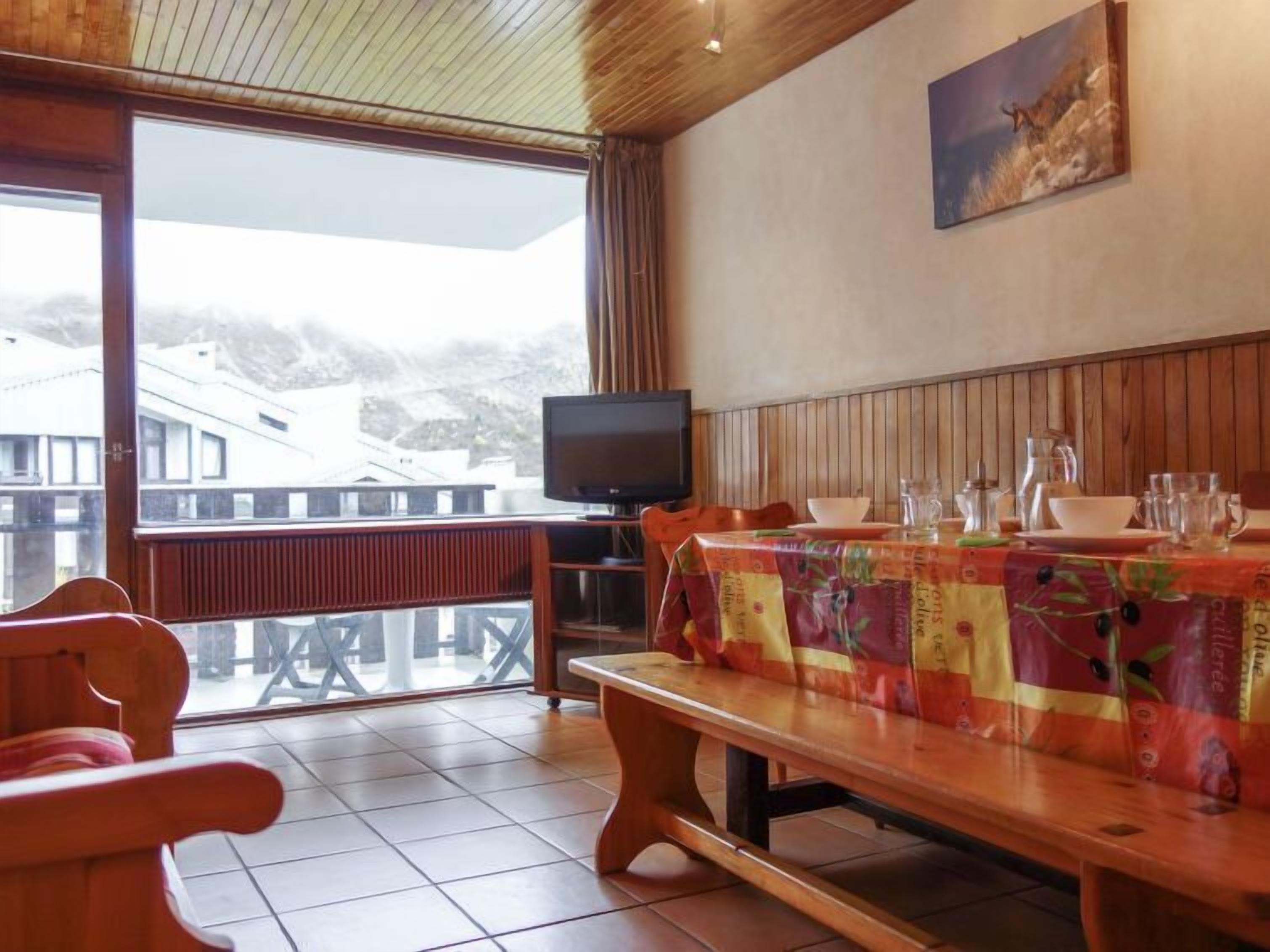 Ein Essbereich mit Holztisch, Bänken und einem Fernseher.