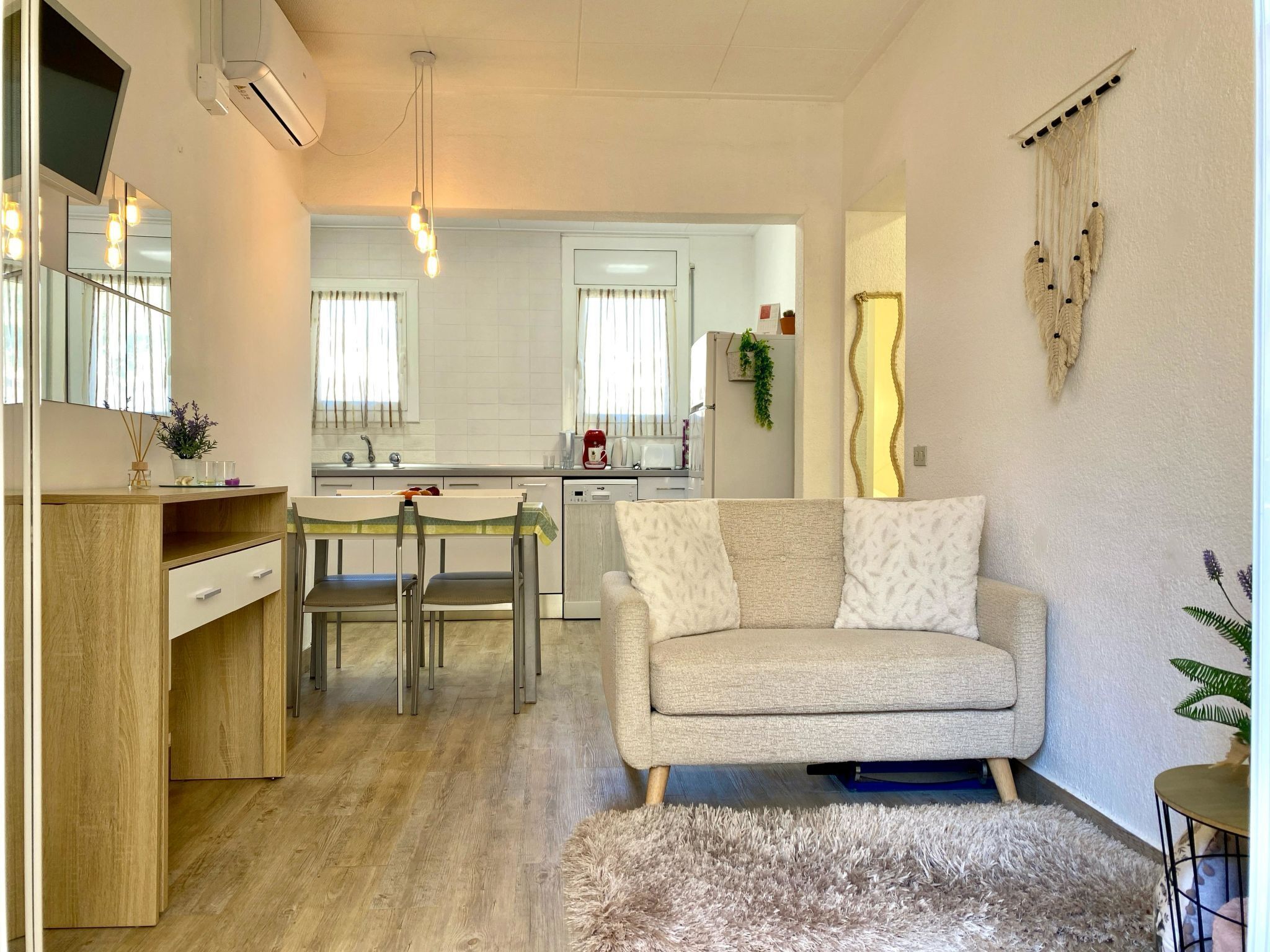 Una sala moderna con un sofá, un escritorio de madera y un comedor.