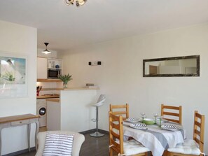 A compact living space with a dining area, kitchenette, and a single bed.