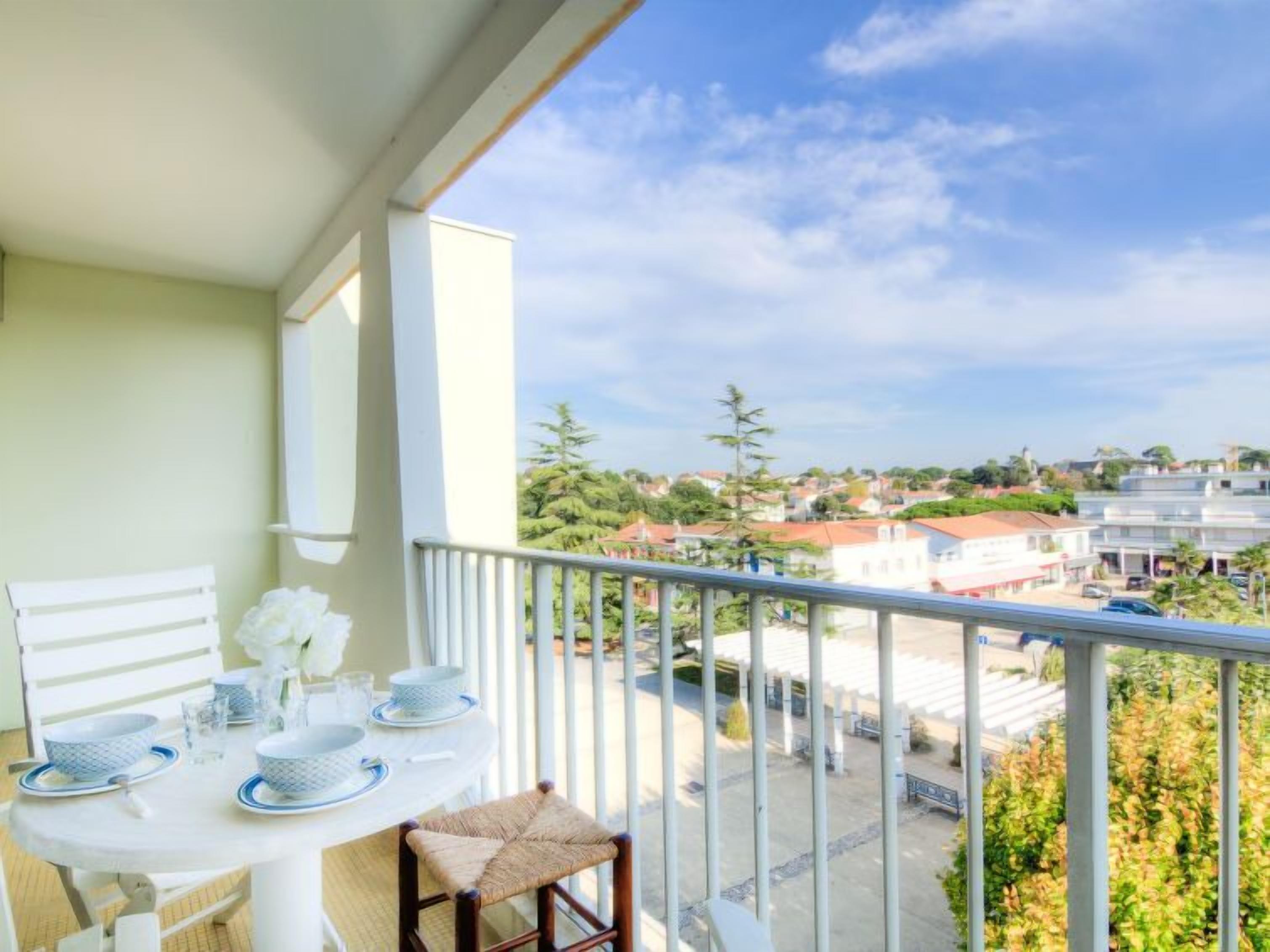 Een balkon met een eettafel, met uitzicht op een woongebied.