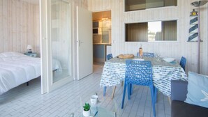 Ein modernes Zimmer mit einem Bett, einem Essbereich mit Tisch und Stühlen, einer Küchenzeile und einem großen Spiegel an der Wand.