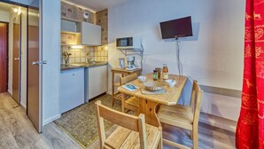 Una cocina compacta con microondas, cafetera y una pequeña mesa de comedor con sillas.
