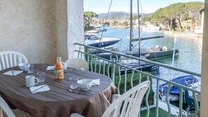 Un balcone con un tavolo apparecchiato per due, affacciato su una marina con barche e cielo sereno.