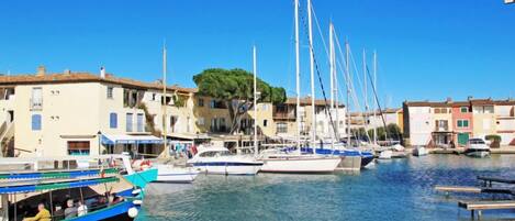 A marina with boats docked, buildings with balconies, and a clear blue sky.