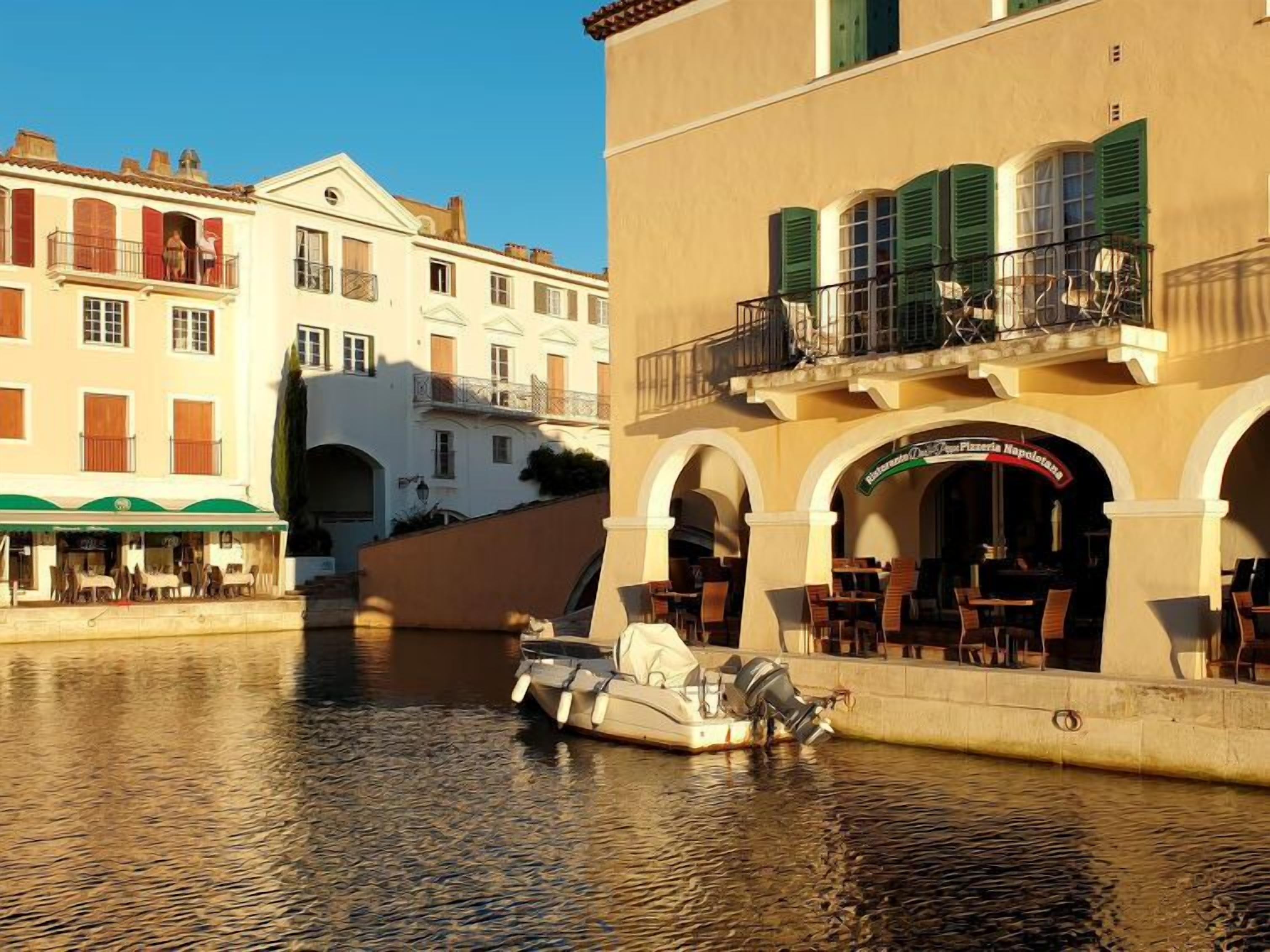 Un canal con un barco atracado cerca de un edificio con terraza y un letrero de restaurante.