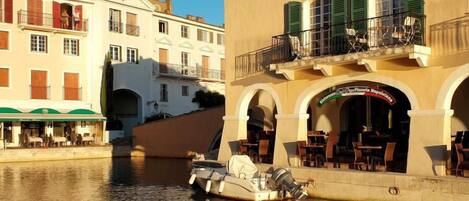 Un canal con un barco atracado cerca de un edificio con terraza y un letrero de restaurante.
