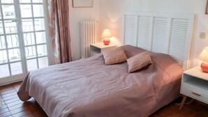 Una camera da letto con un letto, due lampade da comodino, un termosifone e una finestra con tende.
