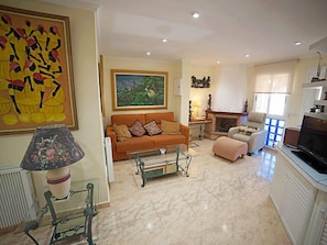 Uma sala de estar com sofá, mesa de centro, televisão e lareira.