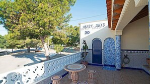 A patio with a decorative fence, a sign reading "HAPPY DAYS 30", and a tiled wall with blue and white patterns.