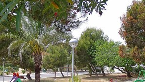 A park with playground equipment, a street lamp, and trees.