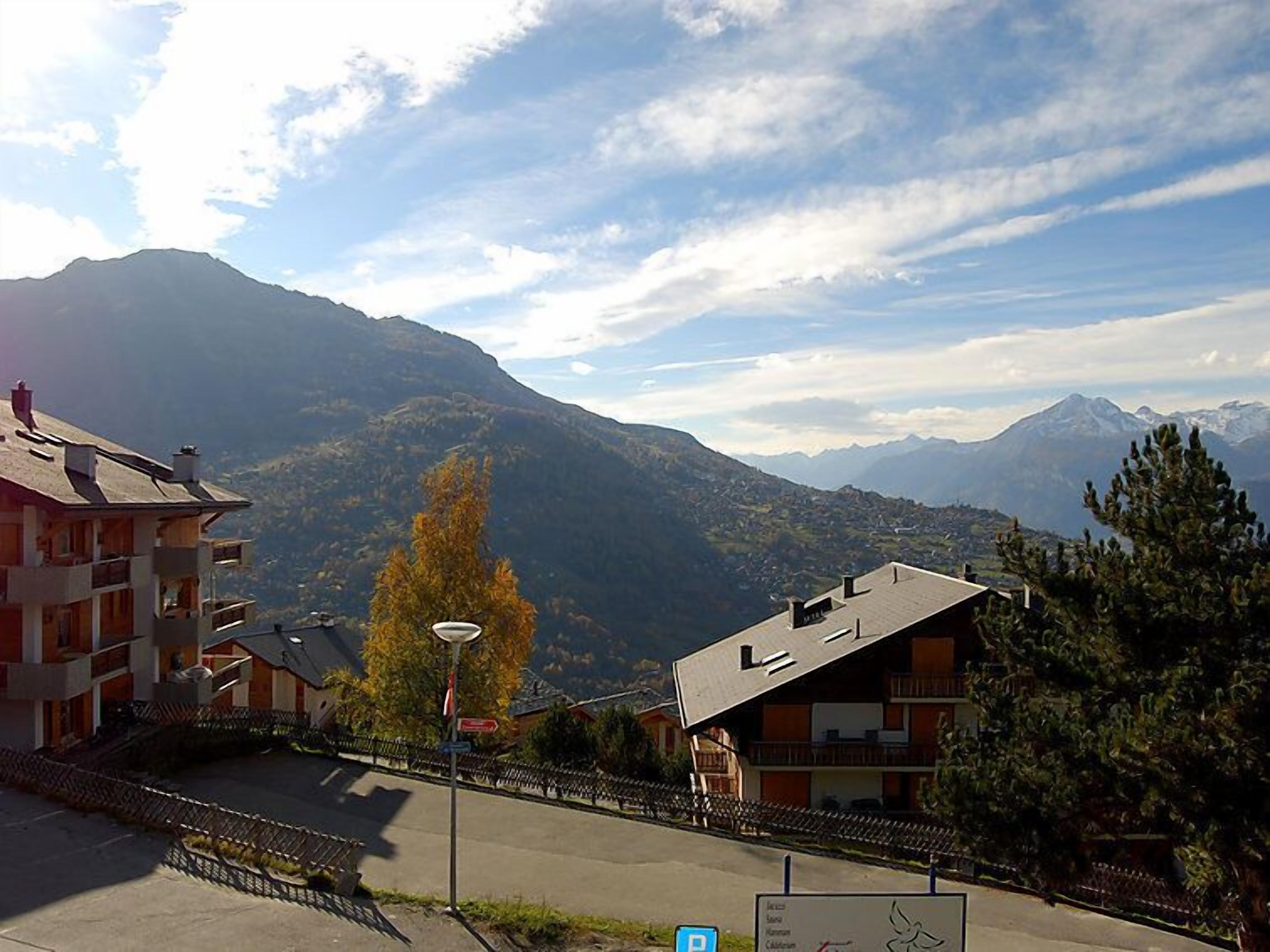 Une vue sur la montagne avec des bâtiments, un panneau indiquant un parking et un ciel dégagé.