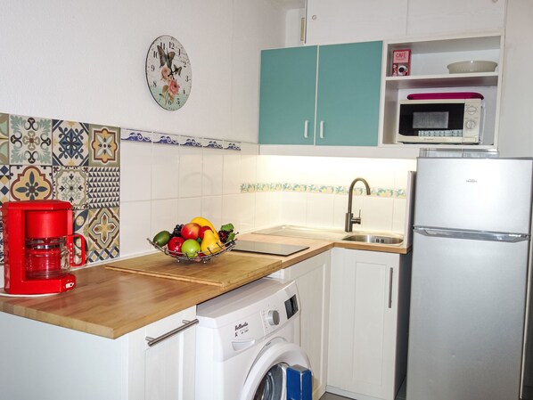 A compact kitchen with a washing machine, a microwave, and a coffee maker.