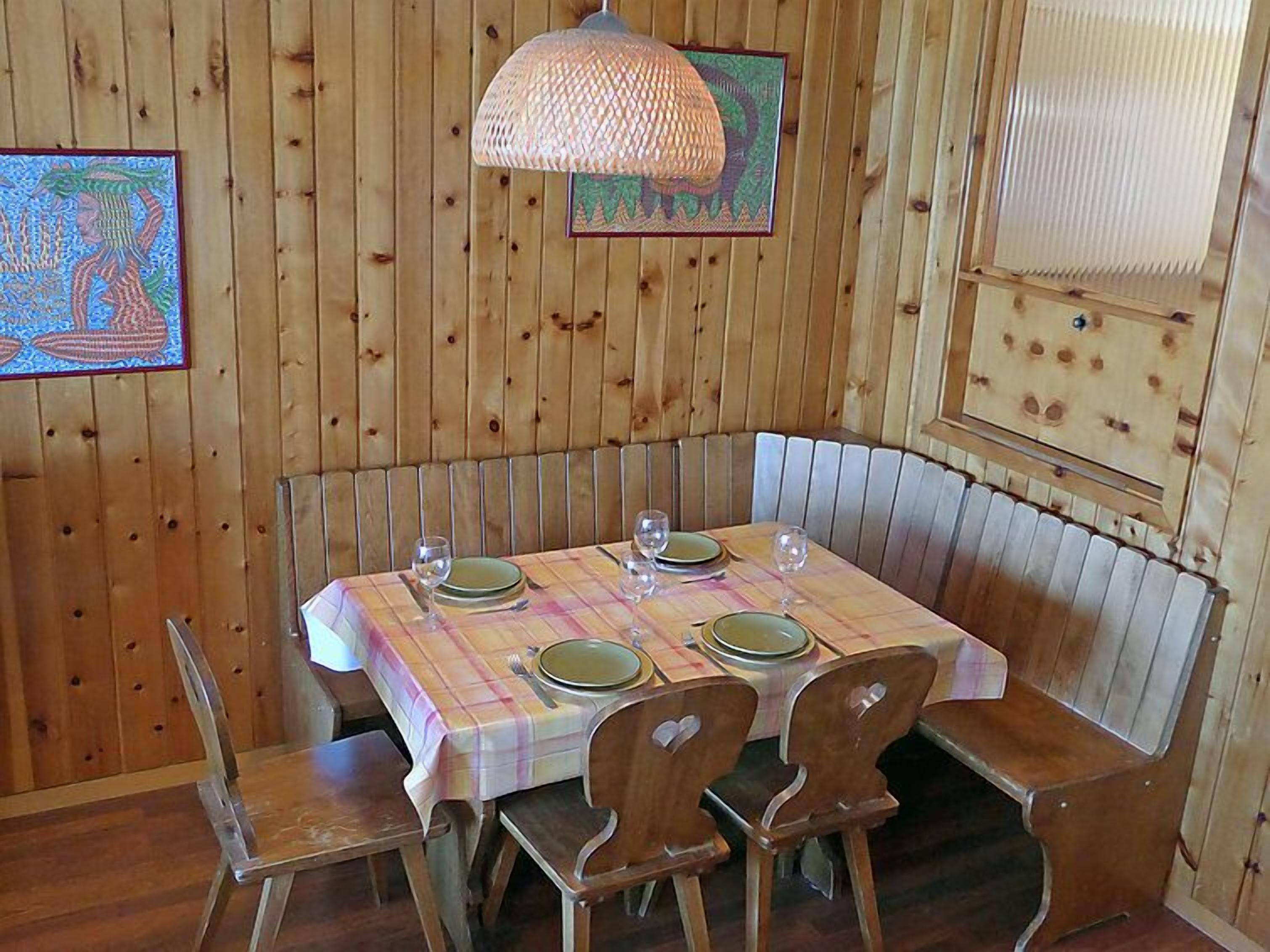 Ein Essbereich aus Holz mit einem Tisch für vier Personen, Bänken und einer Pendelleuchte.